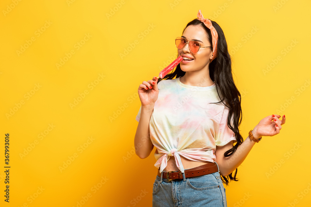 Smiling stylish summer brunette girl with ice cream on yellow background Smiling stylish summer brunette girl with ice cream on yellow background