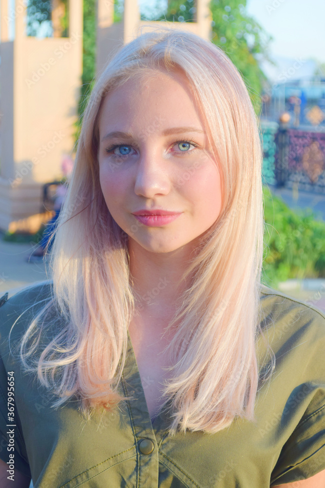 portrait of blonde young woman with blue eyes at a park in daylight portrait of blonde young woman with blue eyes at a park in daylight