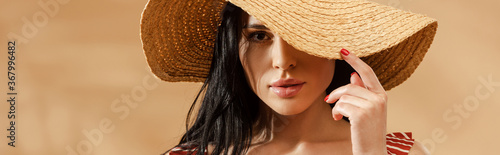 sexy brunette woman in striped swimsuit and straw hat on beige background, panoramic shot