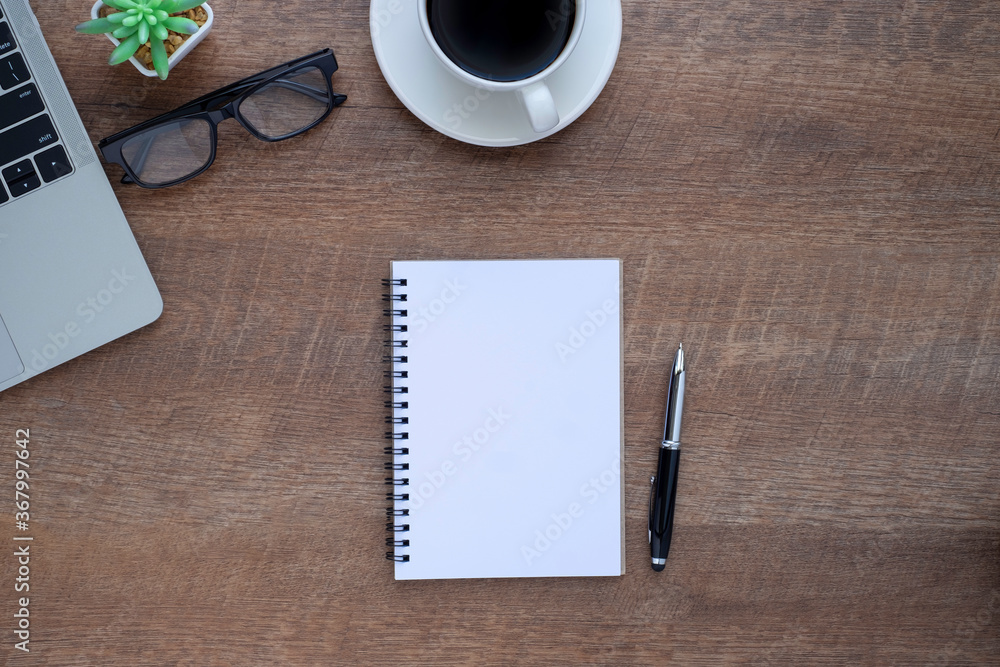 Top view above of Notebook on wooden office desk table with laptop and coffee cup with equipment other office supplies. Top view above of Notebook on wooden office desk table with laptop and coffee cup with equipment other office supplies.