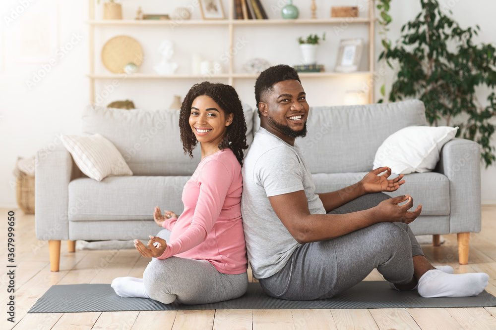 Cheerful african expecting couple exercising together at home Cheerful african expecting couple exercising together at home