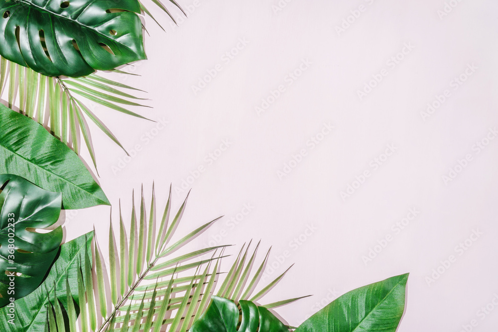 Tropical Jungle Leaves frame with copy space in centre. Pink background.