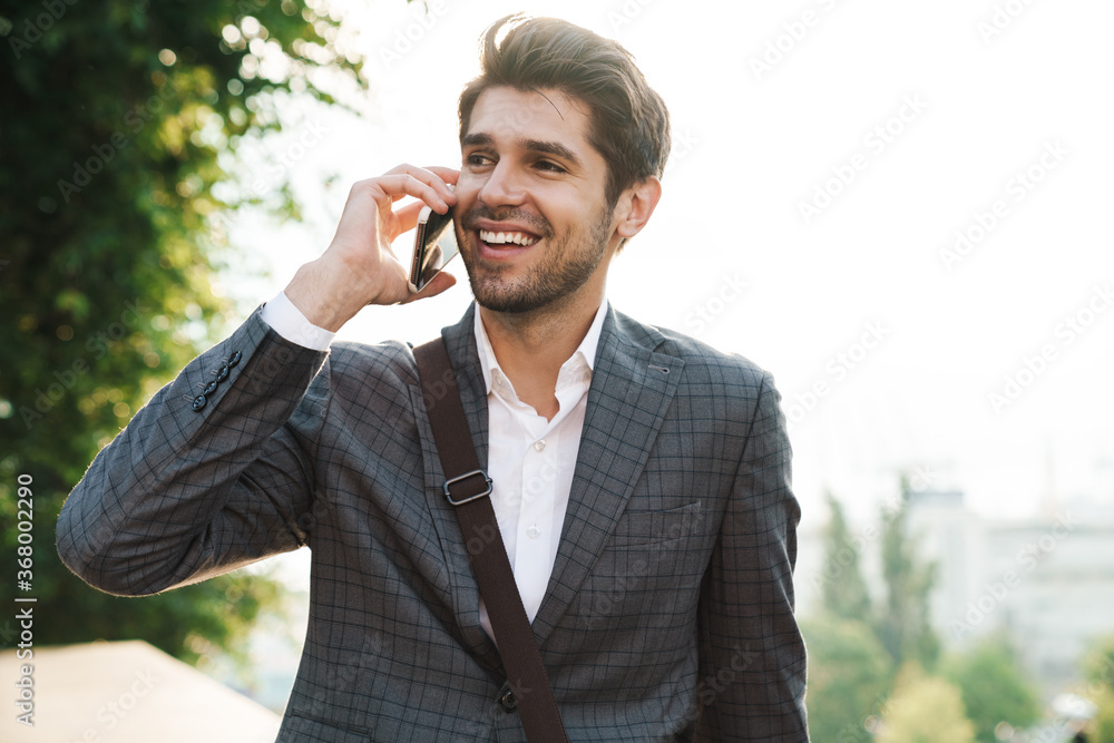 Cheery handsome business man talking by mobile phone Cheery handsome business man talking by mobile phone