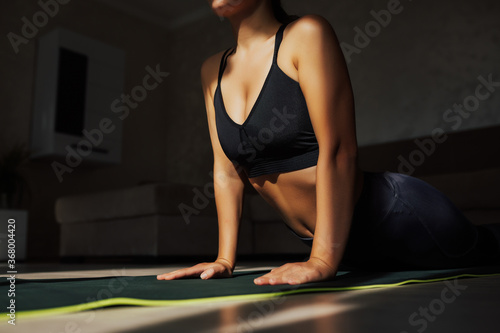 Obraz na płótnie Cropped shot of young girl doing stretching exercise at home. Girl are practicing yoga at home. Sporty woman in sportswear on the floor on mat at home. Calmness concept. w salonie