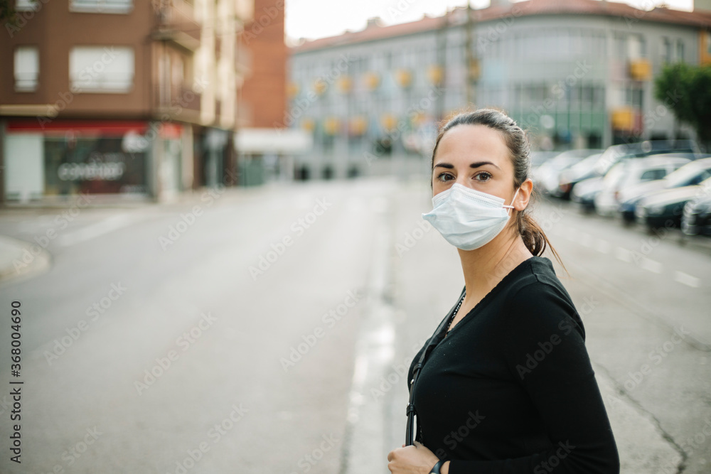 Fototapeta premium Young woman in medical face mask for Coronavirus prevention in the street