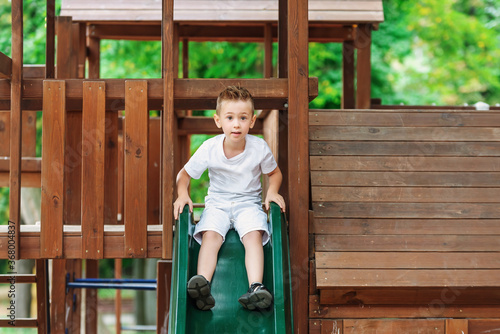 Little Boy Playing At Playground Outdoors In Summer.