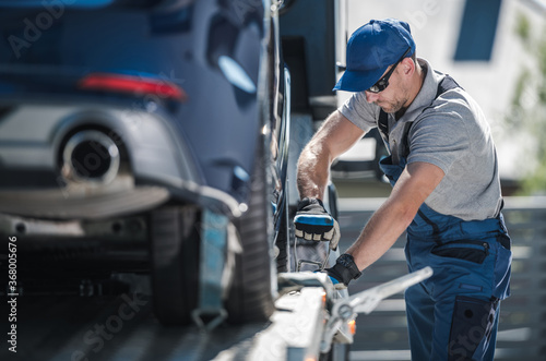 Fotografia Towing Company Worker Securing Vehicle on the Truck Platform