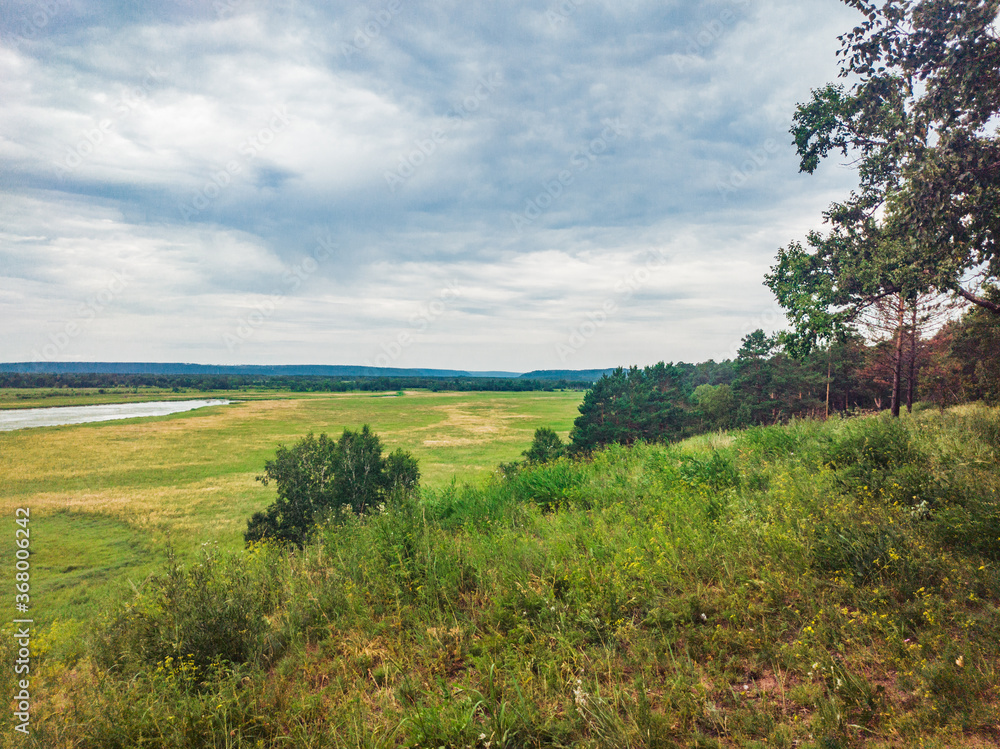 A beautiful view from a high hill to the endless field with a pond and trees in the distance. A beautiful view from a high hill to the endless field with a pond and trees in the distance.