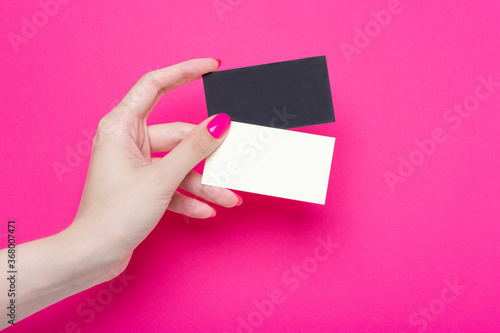 Woman's hands hold two blank business card isolated on pink paper
