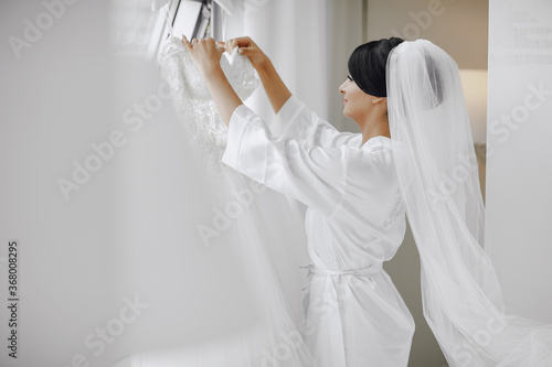 A elegant and beautiful bride at home standing near window