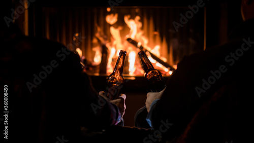 Winter escape - friends relax by the fireplace with beer in their hands