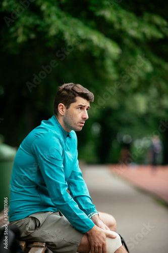 Young man taking rest on the bench. Fit man training outdoors..