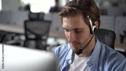 Focused male representative call center agent in wireless headset helping client with complaints using computer in office, corporate operator working in customer support service on helpline telesales photo