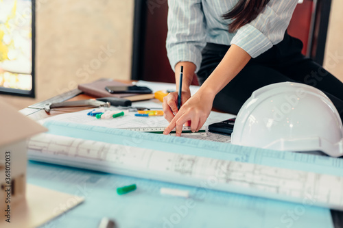 Engineer woman read drawing blue print on table workplace at room site construction. Engineer architect plan concept.