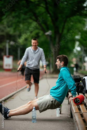 Young men exercising on a race track. Two young friends training in park