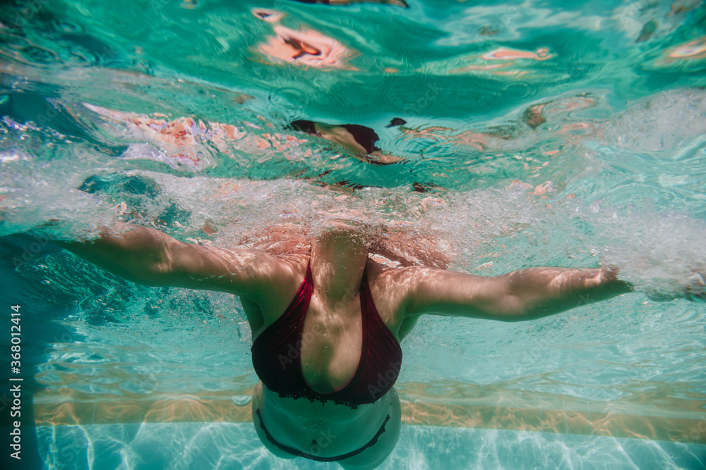 close up view of young woman diving underwater in a pool. summer and fun lifestyle