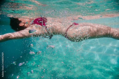 young woman diving floating in a pool. summer and fun lifestyle. selective focus on bubbles.
