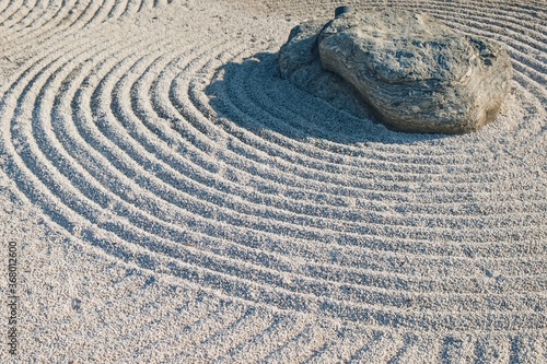 Traditional Details of Classical Japanese Zen Garden. Volcanic stone surrounded concentric lines raked up gravel or sand. Surface of gravel texture with grooves symbolic rows in Gravel Stones Garden.