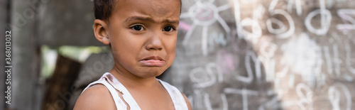 panoramic concept of poor african american boy crying near chalkboard