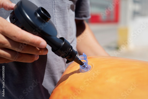 man inflating an orange pool air mattress