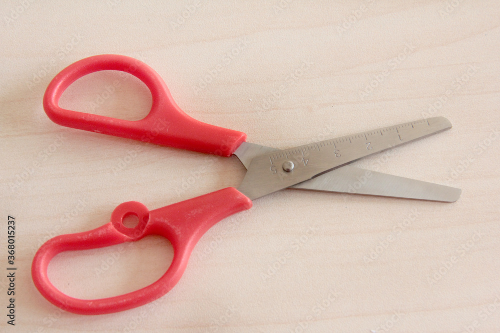 red scissors on wooden background