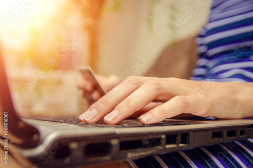 Close-up of a woman's hands holding a credit card and using a laptop. concept of online shopping