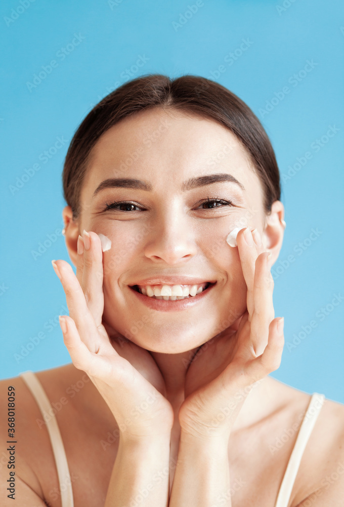 Lovely young woman with healthy skin is applying a cream on her face Lovely young woman with healthy skin is applying a cream on her face