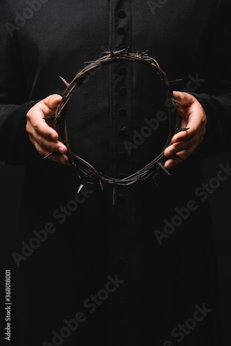 cropped view of pastor holding wreath with spikes isolated on black