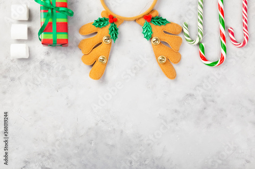 Christmas composition. Gifts, caramel cane, marshmellow, headband antlers on gray concrete background. Concept of winter holidays, new year, Christmas. Top view. Copy space