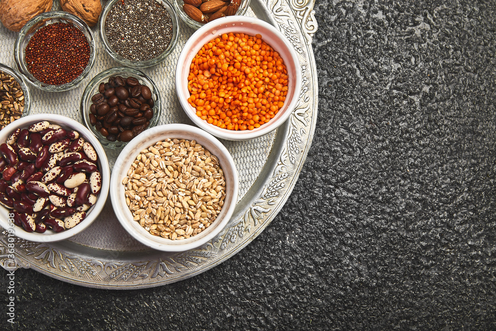 Beans and nuts selection in bowls: quinoa, chia, lentils, beans, almonds, walnuts, coffee beans on dark concrete background copy space Beans and nuts selection in bowls: quinoa, chia, lentils, beans, almonds, walnuts, coffee beans on dark concrete background copy space