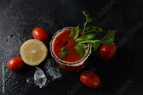 Glass of fresh tomato juice and tomatoes on Dark background with water drops