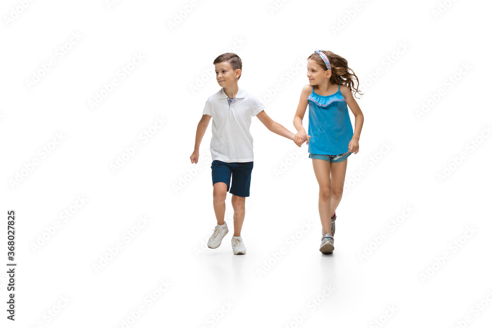 Happy kids, little and emotional caucasian boy and girl jumping and running isolated on white background. Look happy, cheerful, sincere. Copyspace for ad. Childhood, education, happiness concept. Happy kids, little and emotional caucasian boy and girl jumping and running isolated on white background. Look happy, cheerful, sincere. Copyspace for ad. Childhood, education, happiness concept.