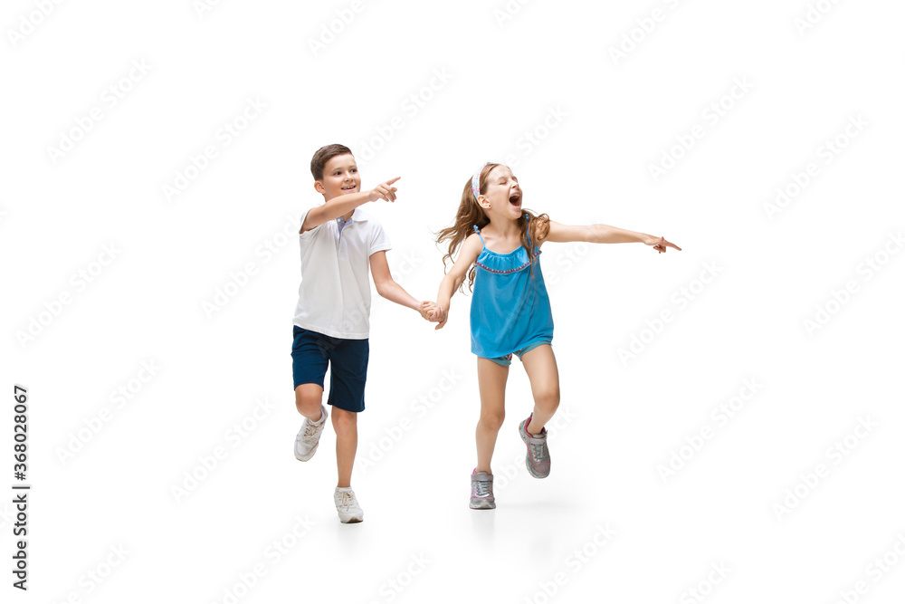 Happy kids, little and emotional caucasian boy and girl jumping and running isolated on white background. Look happy, cheerful, sincere. Copyspace for ad. Childhood, education, happiness concept. Happy kids, little and emotional caucasian boy and girl jumping and running isolated on white background. Look happy, cheerful, sincere. Copyspace for ad. Childhood, education, happiness concept.