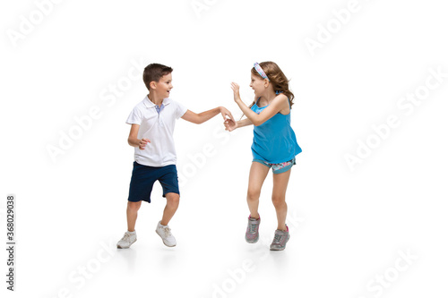 Happy kids, little and emotional caucasian boy and girl jumping and running isolated on white background. Look happy, cheerful, sincere. Copyspace for ad. Childhood, education, happiness concept.