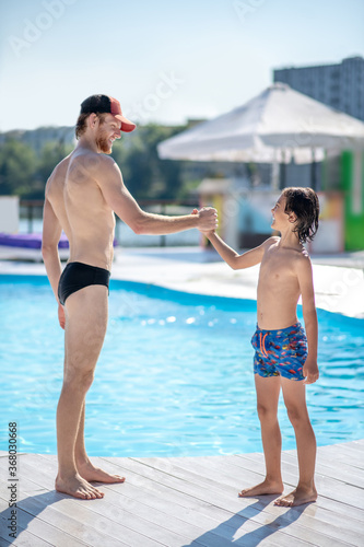 Man and boy standing opposite each other near pool