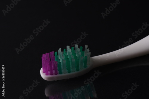 Toothbrush  on black background with water drops 