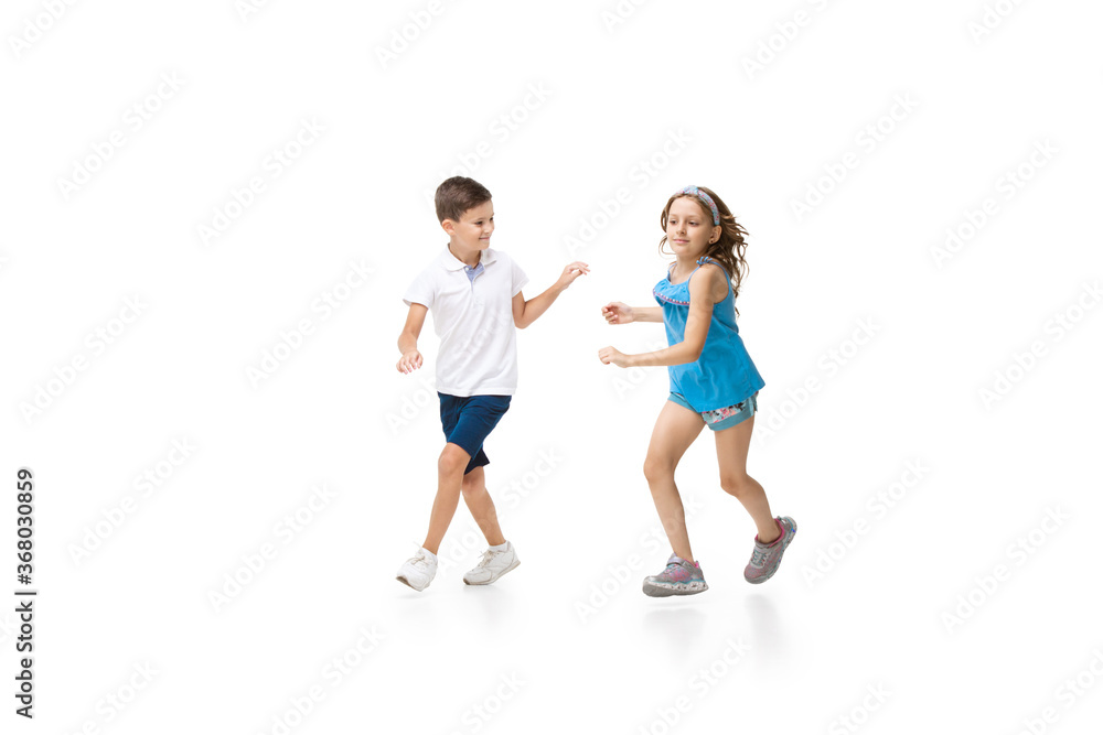 Happy kids, little and emotional caucasian boy and girl jumping and running isolated on white background. Look happy, cheerful, sincere. Copyspace for ad. Childhood, education, happiness concept. Happy kids, little and emotional caucasian boy and girl jumping and running isolated on white background. Look happy, cheerful, sincere. Copyspace for ad. Childhood, education, happiness concept.