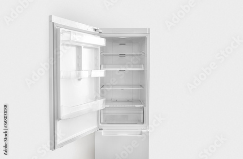 Open white fridge on white wall background
