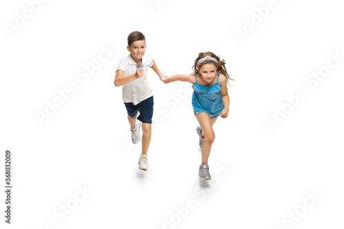 Happy kids, little and emotional caucasian boy and girl jumping and running isolated on white background. Look happy, cheerful, sincere. Copyspace for ad. Childhood, education, happiness concept.