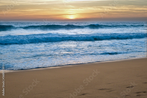 Fototapeta Naklejka Na Ścianę i Meble -  Foamy beach waves with amazing sunset. Endless horizon. Stunning colors