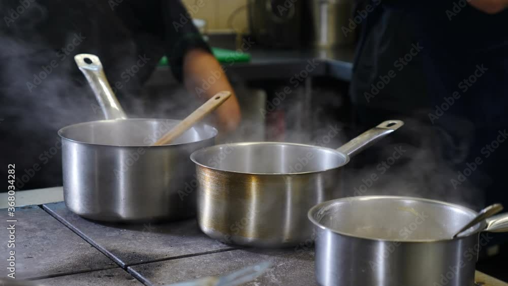 Busy restaurant kitchen concept. Team of chefs and kitchen staff preparing and serving food in commercial kitchen. Rush. Close up. Tossing, pouring sauseand turning frying pan. Shot in 4k Busy restaurant kitchen concept. Team of chefs and kitchen staff preparing and serving food in commercial kitchen. Rush. Close up. Tossing, pouring sauseand turning frying pan. Shot in 4k