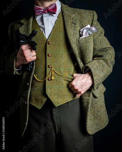 Successful Man in Vintage Tweed Suit Holding Leather Gloves With Thumb in Waistcoat Pocket. Concept of Classic and Eccentric British Gentleman. Vintage Attire. Fashion Model.