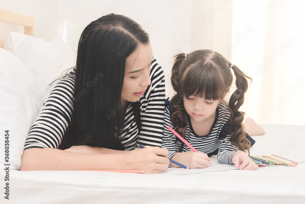 Happy family in the bedroom,Yong mother teaching her daughter child to studying at home.Photo series of family, kids and happy people concept. Happy family in the bedroom,Yong mother teaching her daughter child to studying at home.Photo series of family, kids and happy people concept.