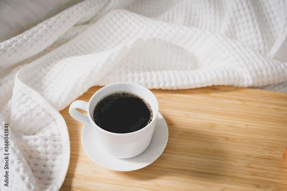Coffee bread in a white cup placed on the bed, white linen during the morning, fresh air Coffee bread in a white cup placed on the bed, white linen during the morning, fresh air