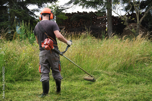 Landscapers men gardeners cutting grass with string lawn trimmers, summer time