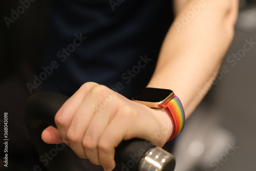 close up man's arm wearing smart watch, exercising on gym equipment. blur background © Robert