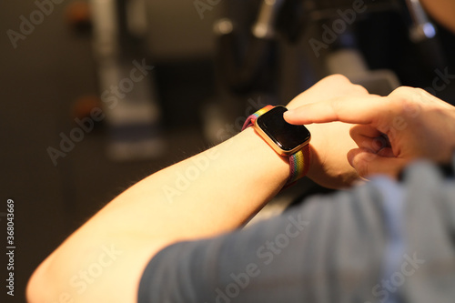 over shoulder of man touching smart watch in gym. blur background