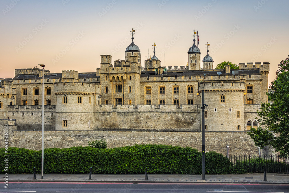 View of Tower of London from outside walls at sunset. Tower of London - historic castle on the north bank of the River Thames in central London - a popular tourist attraction. London, Great Britain.