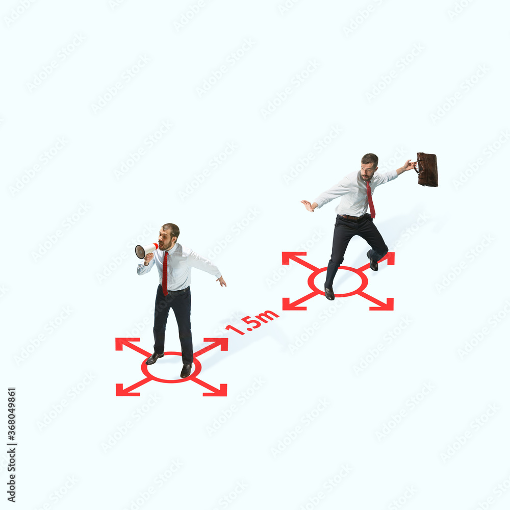Studio shot of people demonstrating social distancing with arrows indicating the separation. Office workers during coronavirus outbreak with new rules for safety and healthcare. High angle view Studio shot of people demonstrating social distancing with arrows indicating the separation. Office workers during coronavirus outbreak with new rules for safety and healthcare. High angle view