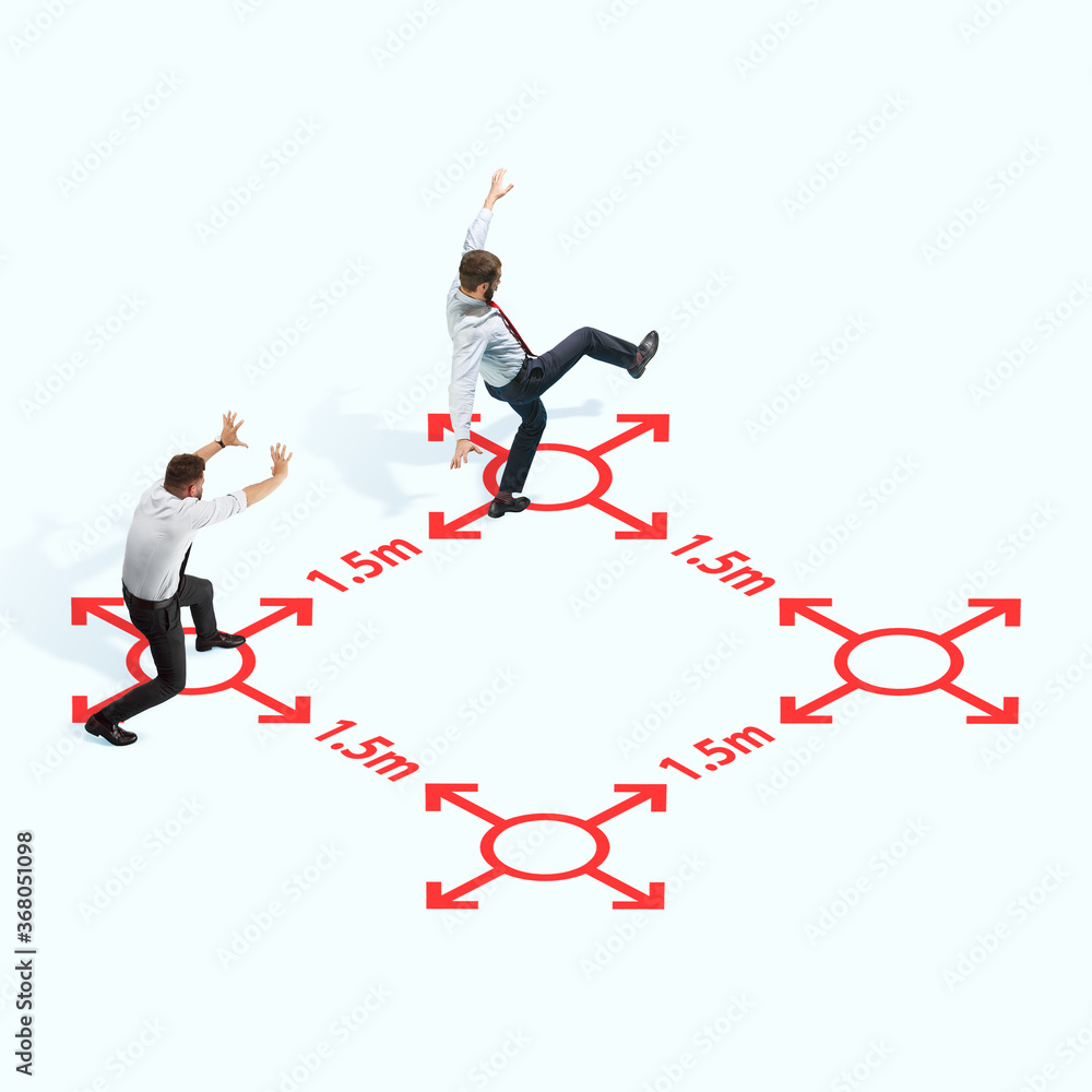 Studio shot of people demonstrating social distancing with arrows indicating the separation. Office workers during coronavirus outbreak with new rules for safety and healthcare. High angle view Studio shot of people demonstrating social distancing with arrows indicating the separation. Office workers during coronavirus outbreak with new rules for safety and healthcare. High angle view